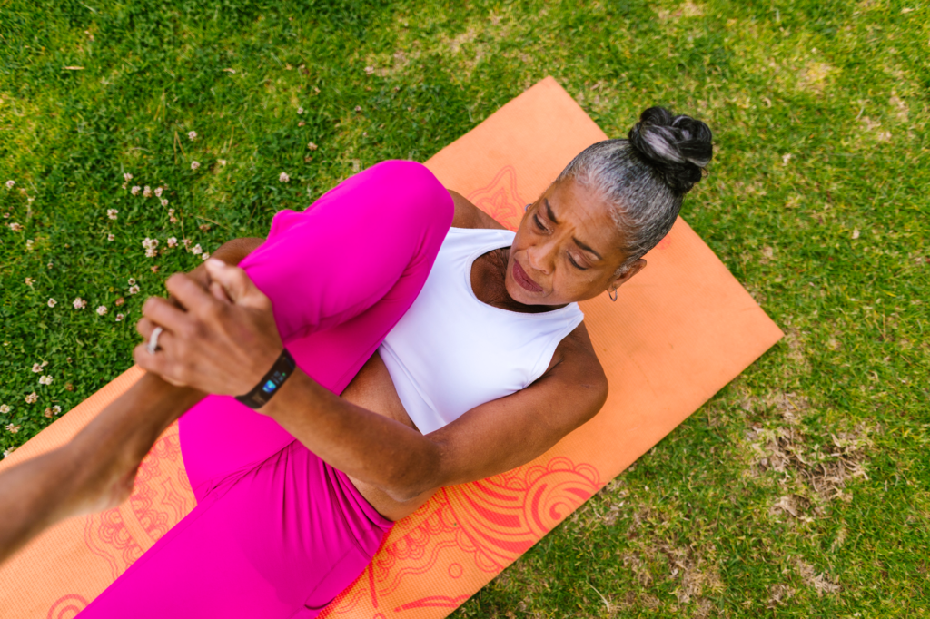 Older lady lying on a yoga mat doing stretches with a focused look on her face